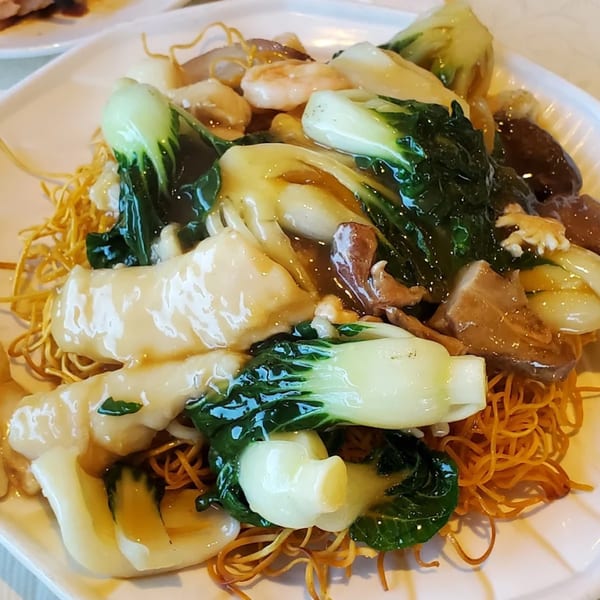 Crispy chow mein noodles topped with bok choy, shrimp, and other ingredients in a savory sauce.