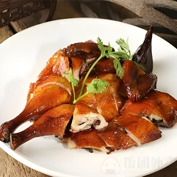 Crispy roasted duck, cut into pieces, garnished with cilantro on a white plate at Tin's Teapot Bistro.